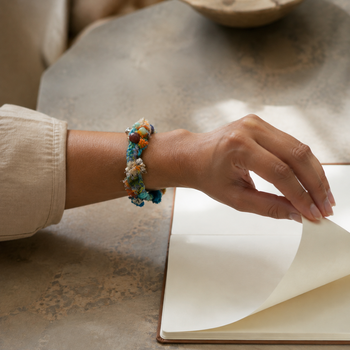 AI-generated styling illustration of the Cove Echo teal, orange and cream bracelet worn on a wrist.