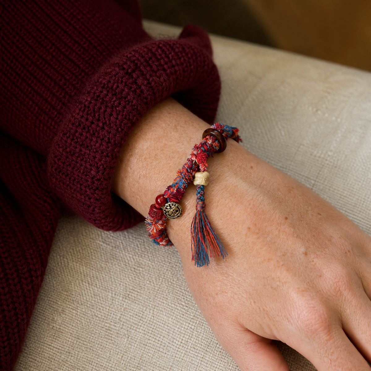 AI-generated styling illustration of the Dusk Ember red, blue and cream bracelet worn on a wrist.